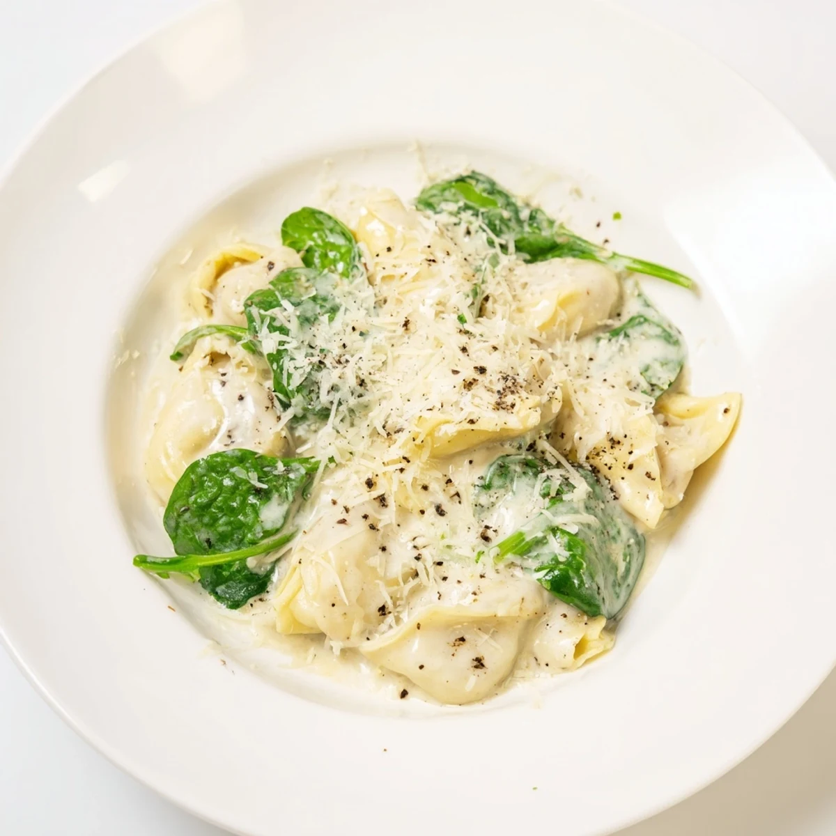 Vibrant green spinach highlights this creamy spinach Alfredo tortellini dish, ready in just thirty minutes.