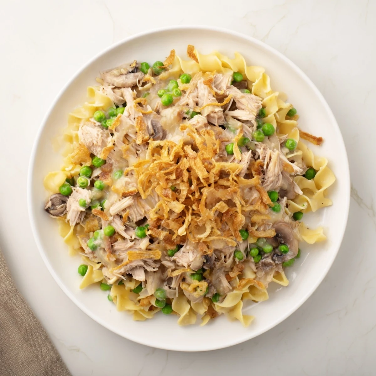 Creamy tuna noodle casserole with golden, bubbly edges, topped with crispy fried onions ready to serve.