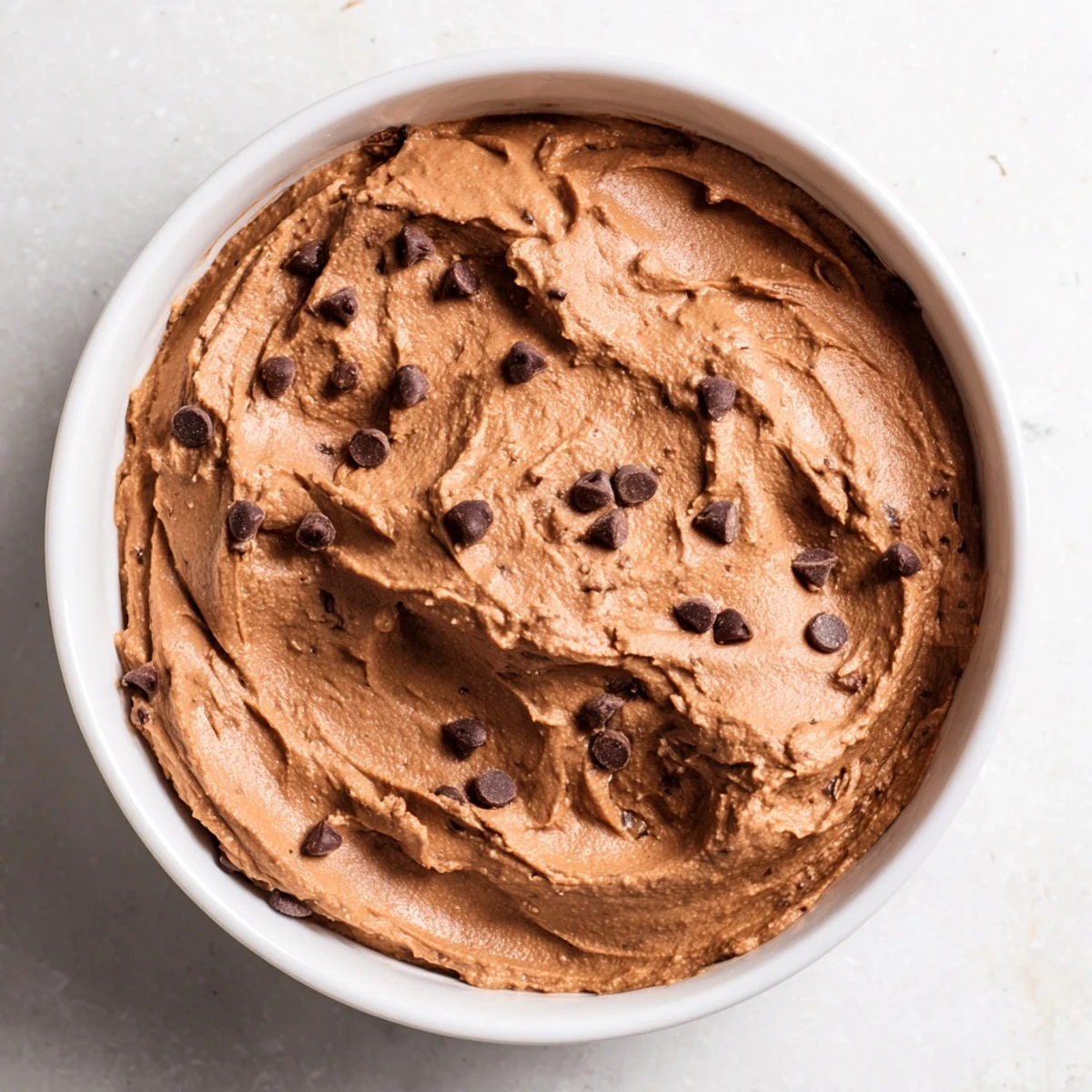 A close-up of creamy chocolate hummus, perfect for dipping strawberries or pretzels.