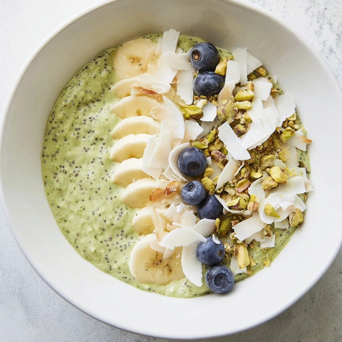 Vibrant green matcha overnight oats, creamy texture visible, topped with fresh berries and coconut flakes.