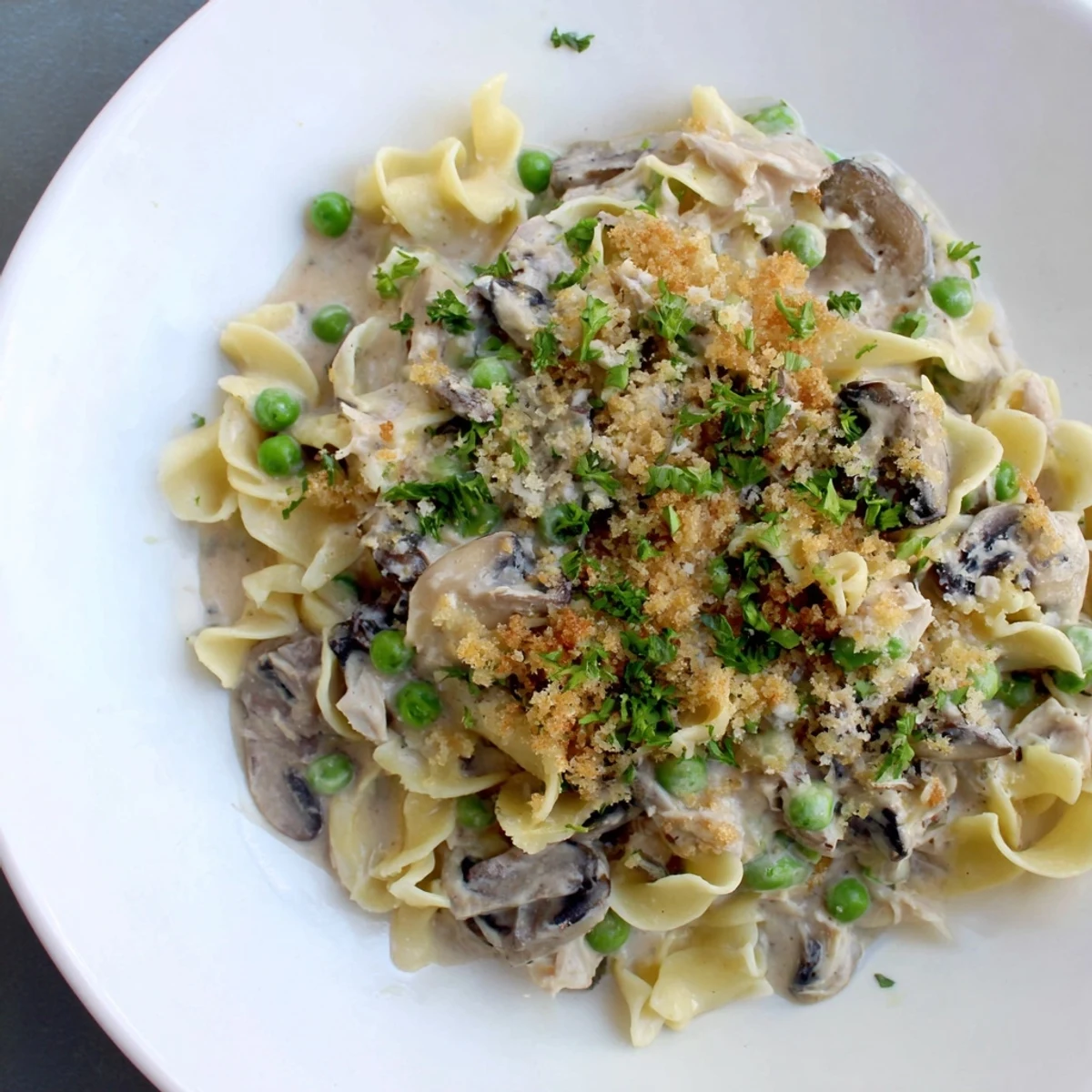 Golden, bubbly Tuna Noodle Casserole topped with crispy panko, ready to serve with fresh parsley.