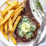 Tender ribeye steak topped with rich garlic butter, complemented by golden, crunchy fries.  