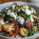 A vibrant Roasted Brassica Bowl topped with pumpkin seeds and fresh parsley, drizzled with creamy tahini-lemon dressing.