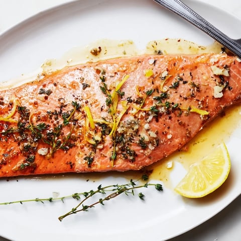 Succulent lemon thyme roasted salmon fillets garnished with fresh herbs and lemon slices.  