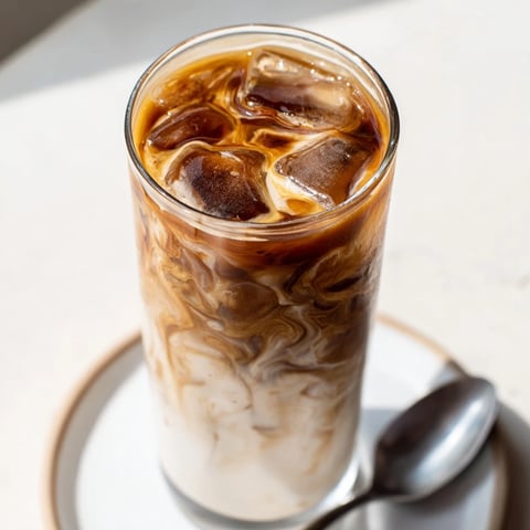 Rich tahini iced coffee served over ice with creamy plant-based milk swirls.  
