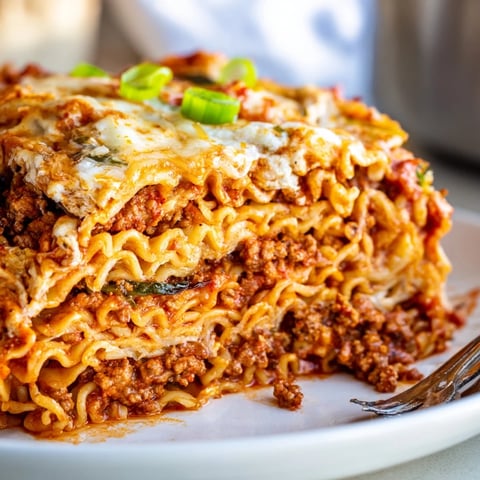 Layers of spicy ramen lasagna topped with bubbling cheese and green onions.  