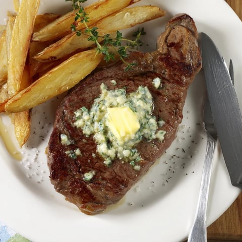 Juicy steakhouse garlic butter steak served alongside crispy golden fries, perfect for dinner.  