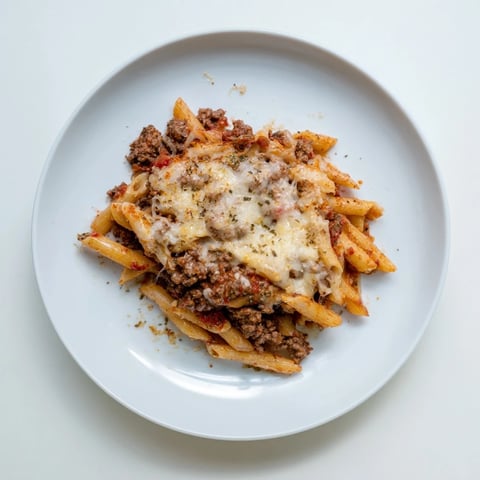 A bubbling Cheesy Beef & Penne Bake topped with melted mozzarella cheese and herbs.  