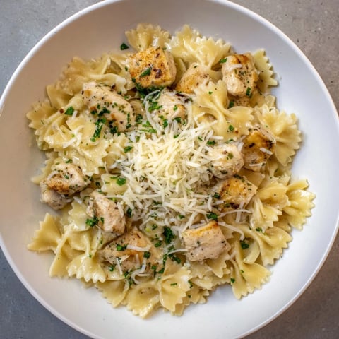 Golden brown mozzarella topping the garlic butter chicken bowties, a comforting Italian-American meal.