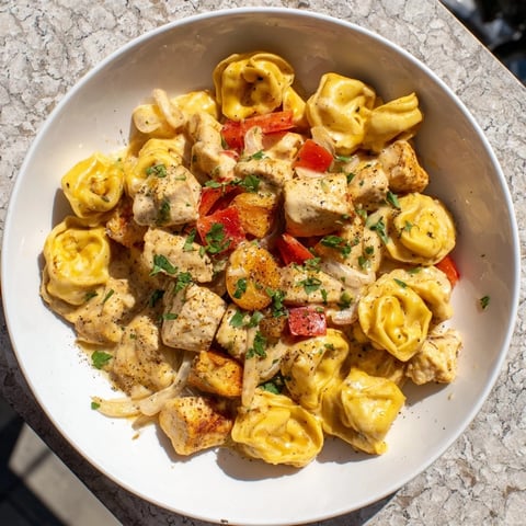 Zesty Cajun Garlic Parmesan Chicken Tortellini, a creamy, golden pasta dish with fresh parsley garnish.