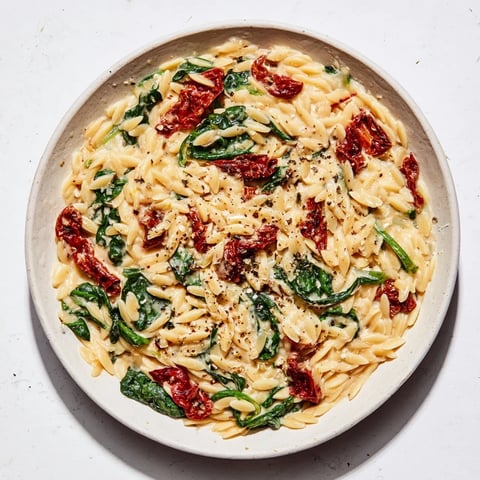 Creamy Tuscan Orzo Bowl with sun-dried tomatoes and spinach, ready for a comforting vegetarian dinner.
