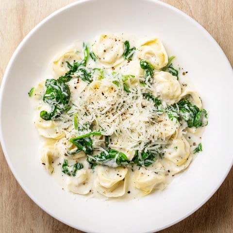 Golden, creamy spinach Alfredo tortellini, a comforting Italian dinner ready with fresh Parmesan.