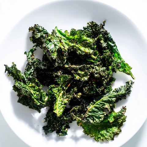 Golden, crispy baked kale chips, a healthy snack with sea salt and pepper seasoning.