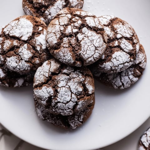 Freshly baked Chocolate Gingerbread Crinkle Cookies dusted with powdered sugar, ready to enjoy.