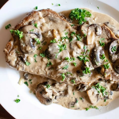Golden-brown stovetop pork chops smothered in creamy mushroom sauce, perfect for a cozy dinner.