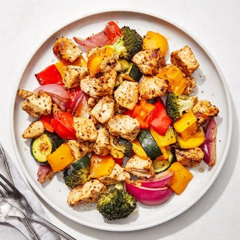 Golden Garlic Parmesan Chicken Bites, roasted alongside colorful vegetables for a simple sheet pan dinner.