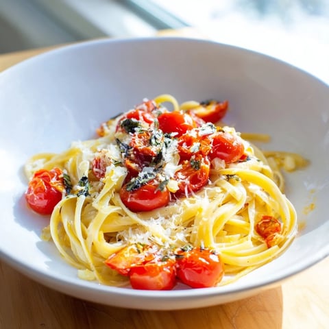 A steaming bowl of Cozy Fireplace One-Pan Tomato Basil Pasta with fresh basil garnish.