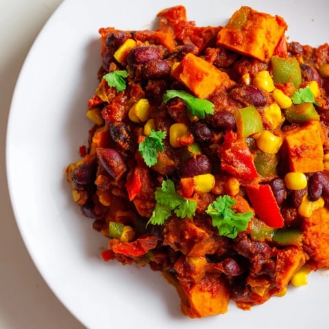A steaming bowl of Smoky Sweet Potato Chili, filled with colorful vegetables and savory spices.