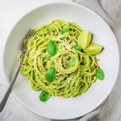 Golden spaghetti coated in creamy smashed avocado sauce, with lime zest, chili flakes, and fresh basil garnish.  