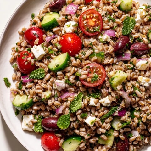 A vibrant Farro Salad Mediterranean tossed with juicy tomatoes, crisp cucumber, briny olives, and creamy feta in a zesty lemon dressing.