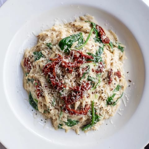 Flavorful Creamy Tuscan Orzo Bowl, garnished with Parmesan cheese, promising a savory Italian meal.