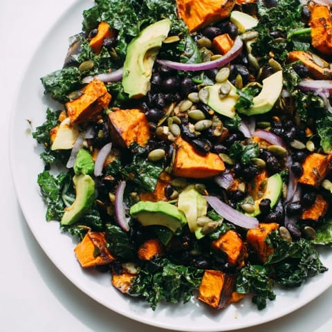 Close-up of a colorful massaged kale salad with roasted sweet potatoes and creamy avocado.