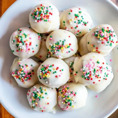 Freshly baked Protein-Packed Italian Christmas Cookie Balls, glistening with a vanilla glaze and colorful sprinkles.