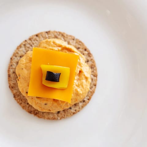 Homemade Santa's Belt Crackers feature melted cheese, a flavorful red pepper dip, and olive belt details.