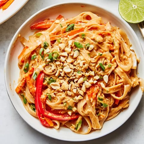 Close-up of freshly made Spicy Peanut Noodles, coated in a rich peanut sauce, garnished with cilantro.