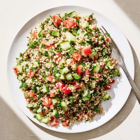 Fork-tender Bulgur Wheat Salad Tabbouleh tossed with zesty lemon dressing and fresh mint leaves on a rustic table.