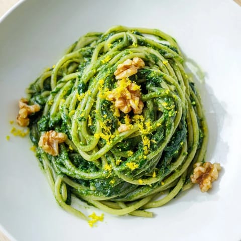 Creamy Spinach Walnut Pasta in a rustic white bowl, garnished with fresh black pepper and lemon zest.  