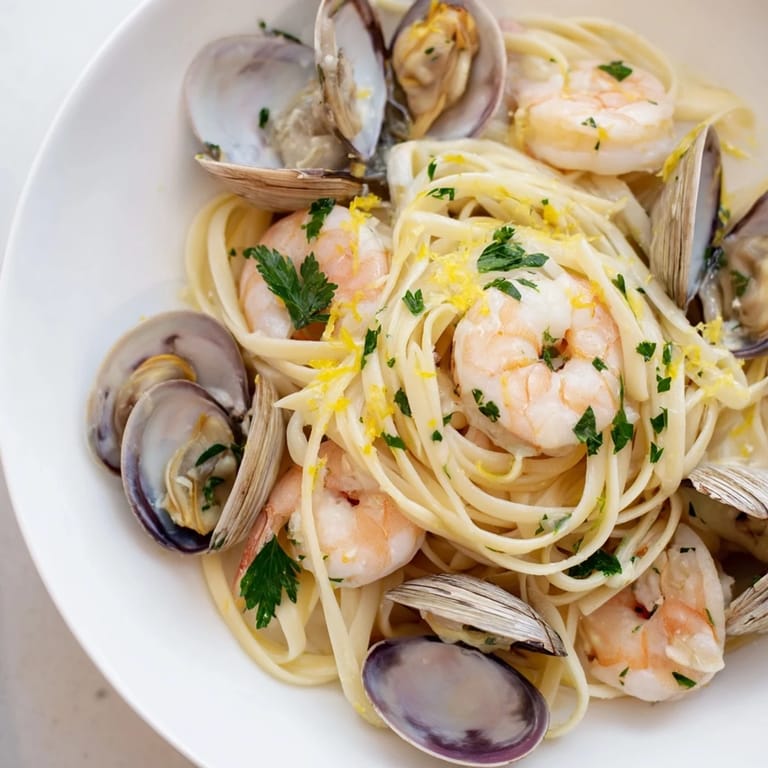 A rustic skillet of Seafood Linguine featuring plump shrimp and mussels, steaming in a fragrant lemon-garlic broth over al dente pasta.