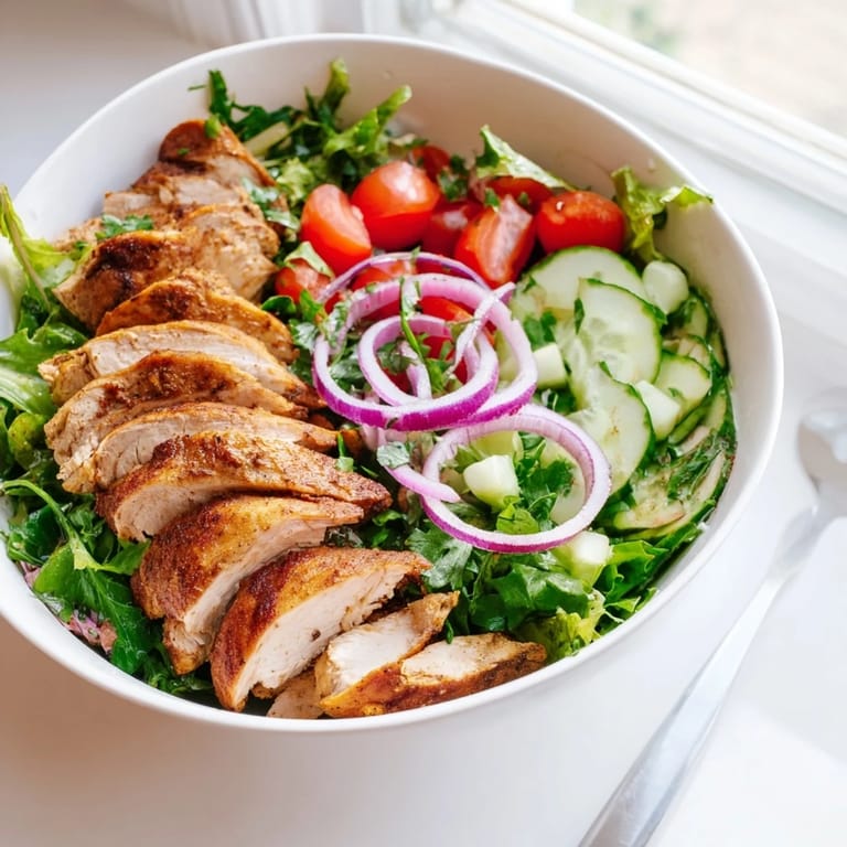 Healthy gluten-free chicken shawarma salad bowl with tender sliced chicken, vibrant vegetables, and yogurt garlic sauce for lunch.