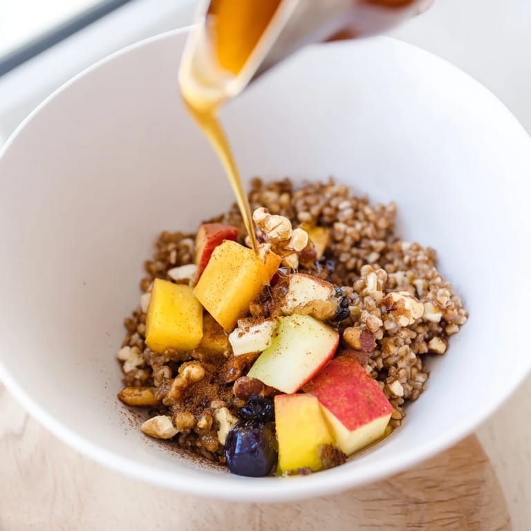 Steaming Buckwheat Groats Breakfast in a rustic bowl, garnished with mixed nuts and vibrant fruit, ready to enjoy with a splash of milk.  