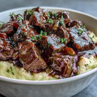 Tender venison simmered in a rich, aromatic sloe gin sauce, spooned over creamy, buttery Parmesan polenta for a comforting winter meal.