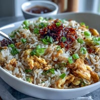 Crispy chili crisp egg fried rice with fluffy scrambled eggs, scallions, and a spicy chili oil drizzle.  